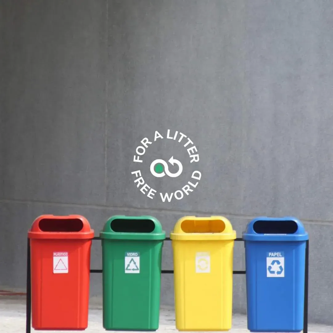 Four labeled recycling bins for plastic, glass and paper at a waste collection point Four labeled recycling bins for plastic, glass and paper at a waste collection point
