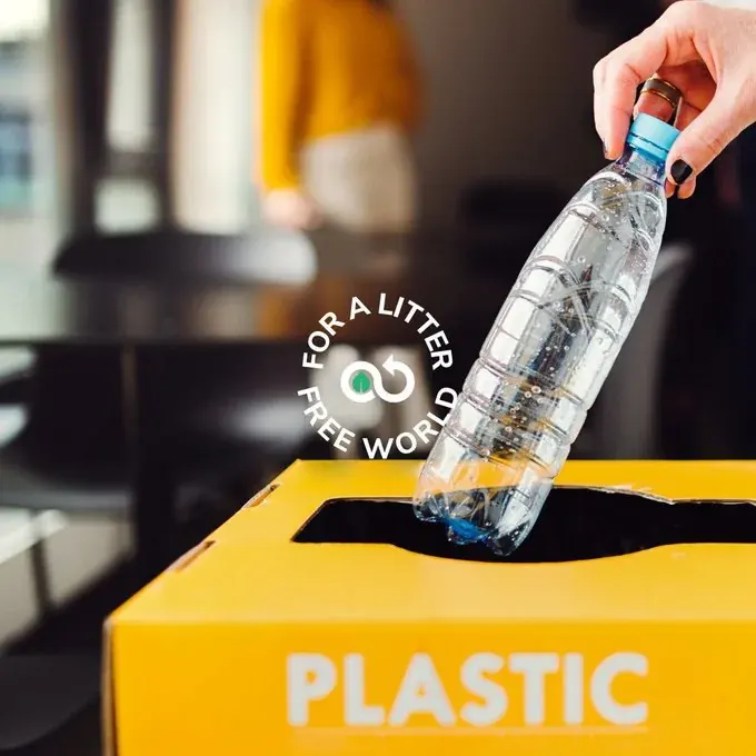 Person placing a plastic bottle into a plastic recycling bin for collection in the UAE Person placing a plastic bottle into a plastic recycling bin for collection in the UAE