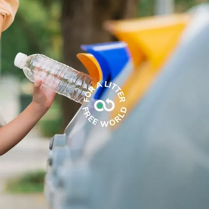 Hand holding a plastic bottle near a recycling bin outdoors Hand holding a plastic bottle near a recycling bin outdoors
