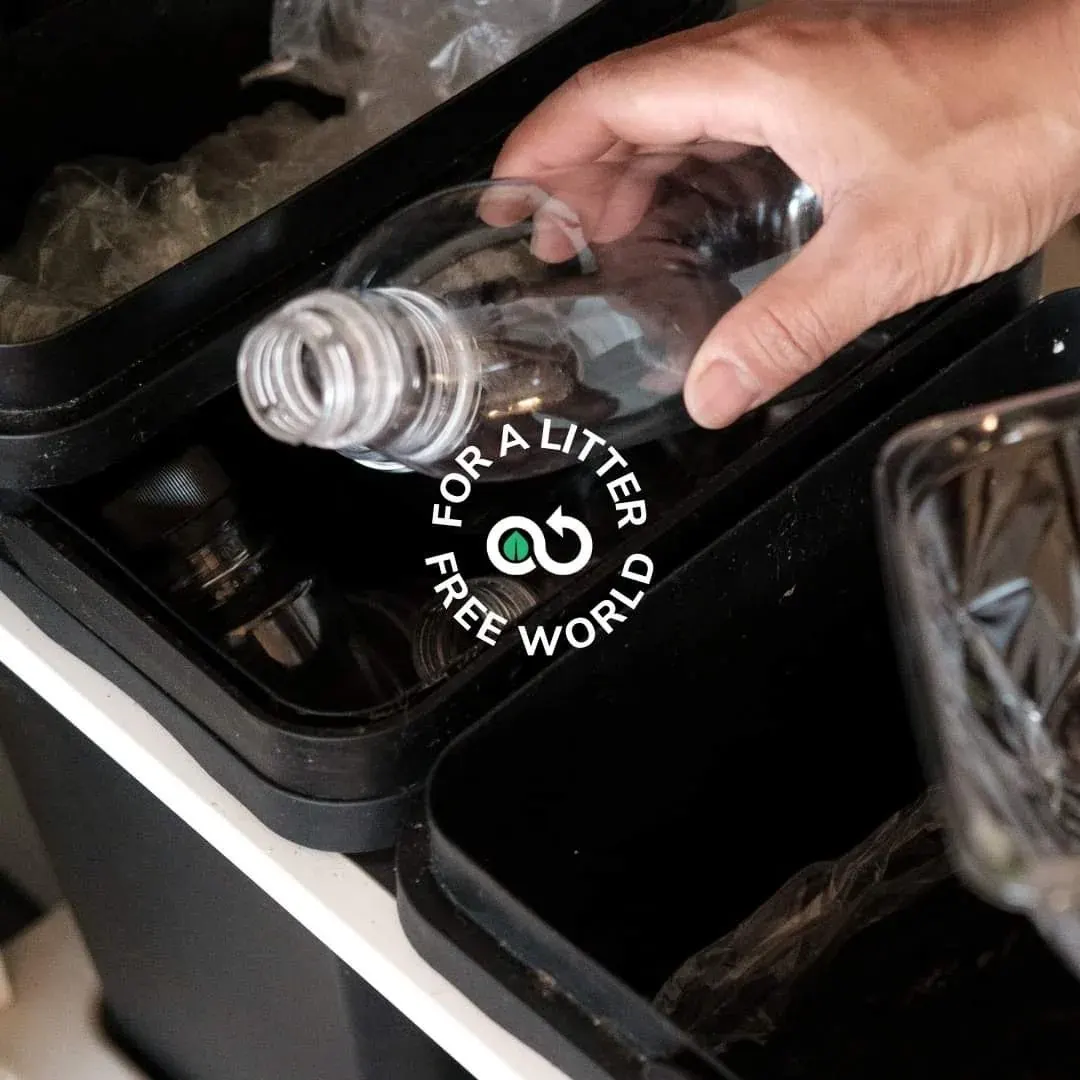 Hand placing a clear plastic bottle into a holder, related to packaging return and collection