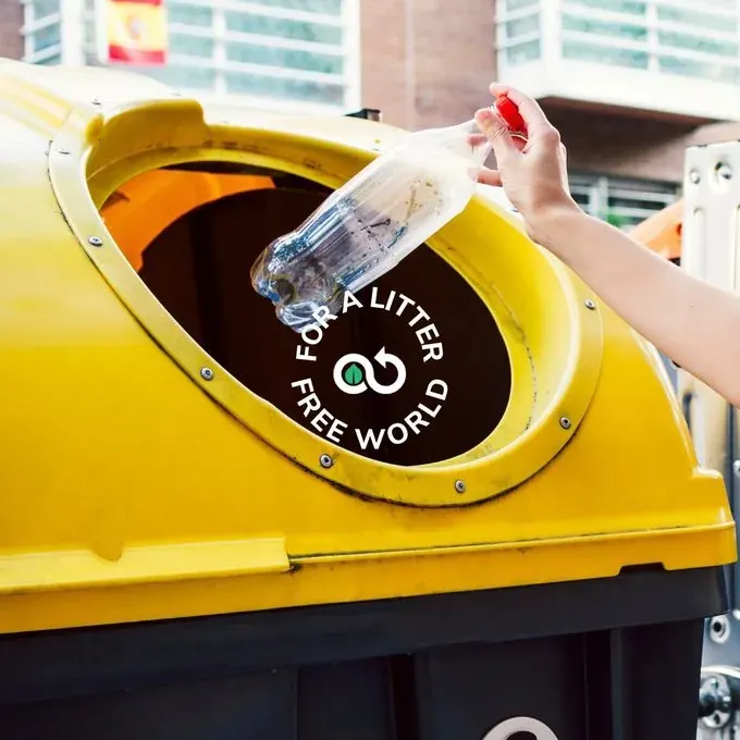 Person placing a plastic bottle into a recycling bin in an urban setting Person placing a plastic bottle into a recycling bin in an urban setting
